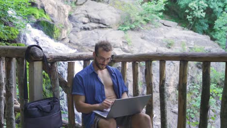 Casual-businessman-working-with-laptop-at-waterfall.
